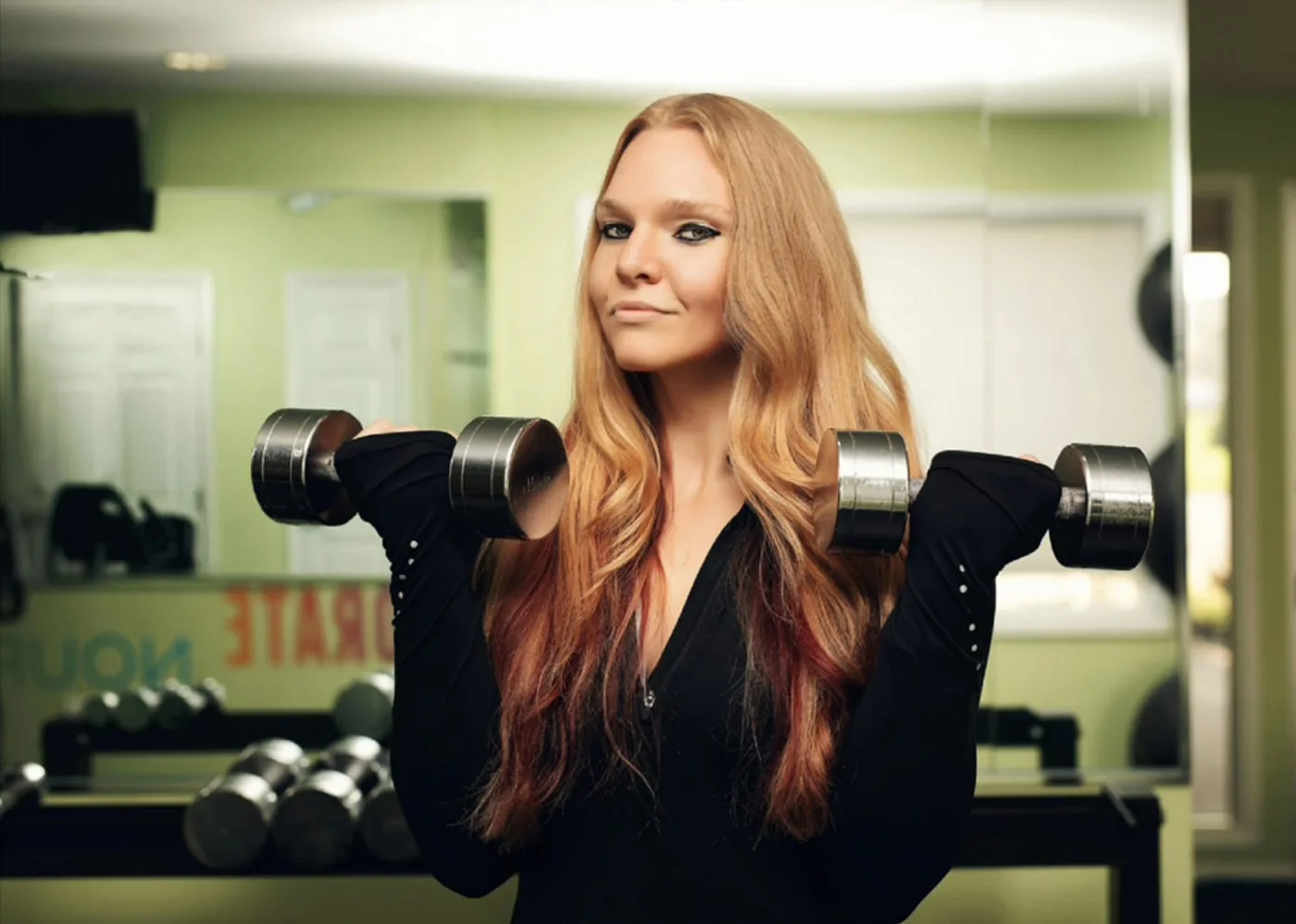 Nicole Konstanzer, certified personal trainer and nutritionist, holding dumbbells in her gym